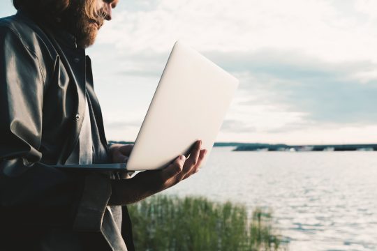 En kanididat som går med en laptop utomhus,